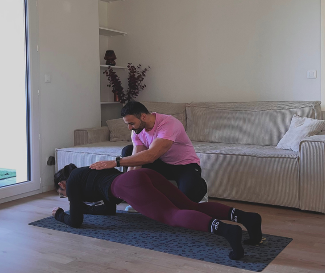 Photo de MatBCoaching en train d'entraîner une jeune femme en gainage sur un tapis chez elle.